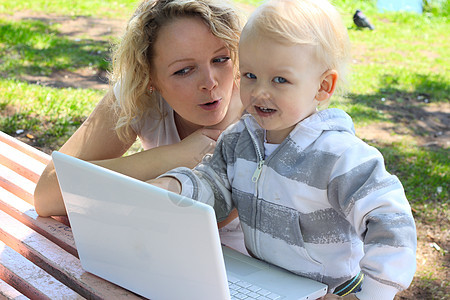 使用手提笔记本电脑的母婴学习童年女儿母亲金发女士女性技术教育草地图片