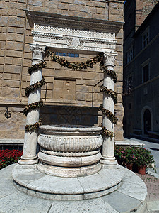 Pienza  大教堂广场上的老井城市拱廊短笛羊乳正方形二人柱子街道柱廊花朵图片