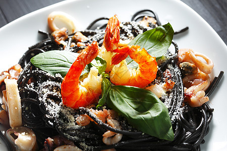黑意面加海鲜盘子贝类叶子沙拉面条午餐桌子食物墨水香料图片