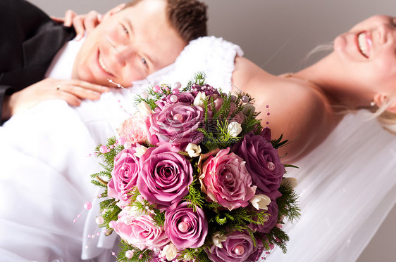 穿着鲜玫瑰花束的结婚礼服的年轻夫妇仪式快乐新娘婚礼妻子男性裙子订婚男人丈夫图片