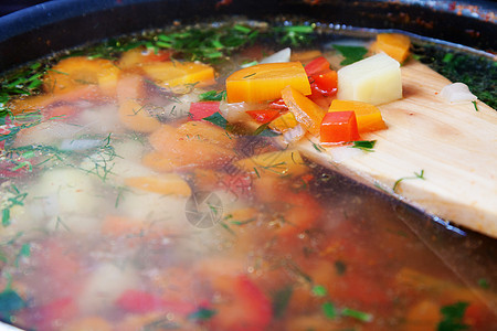 用木勺子在锅里放蔬菜汤图片
