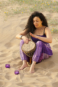 Djembe 玩家赤脚女性阳光工艺蜡烛享受晴天黑发音乐沙丘图片