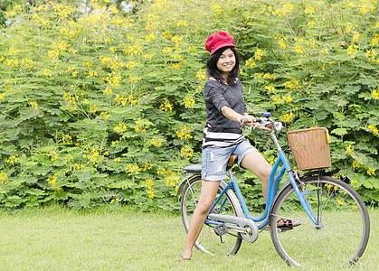 年轻女士坐在绿色草地上 骑着自行车图片
