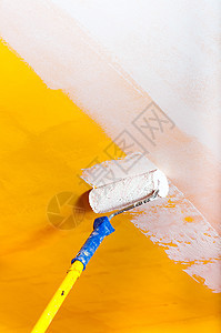 在黄墙上涂白白油漆并挂着画棍工作维修刷子滚筒画笔活动装潢艺术画家房间图片