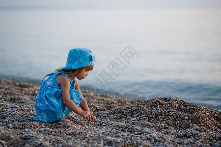 海滩上的小女孩日落童年快乐女儿帽子石头女孩孩子裙子赤脚图片