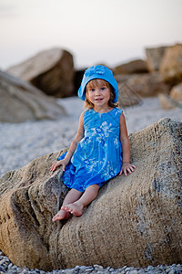 海滩上的小女孩婴儿衣服日落女性乐趣活动场景童年卵石蓝色图片