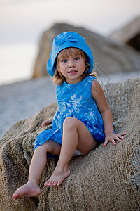 海滩上的小女孩卵石帽子日落石头女儿幸福假期海岸童年海浪图片