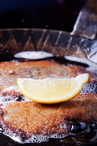 铁锅里有鸡肉脆饼面包屑气泡食物盘子油炸棕色猪肉平底锅肉片柠檬图片