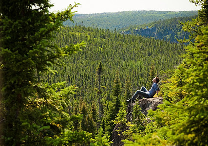 年轻人在大自然中间的岩石上寂寞蓝色荒野森林晴天闲暇悬崖男人男性孤独图片