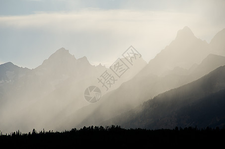 美国怀俄明州Grand Teton国家公园Teton山上空的暴风云中破晓的光线图片