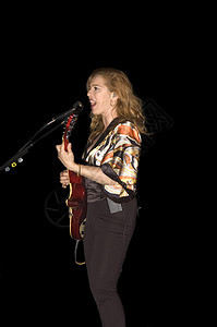 歌手吉他家在现场音乐会中演奏指法居住聚光灯音乐家女性采摘玩家艺人吉他手女士背景图片
