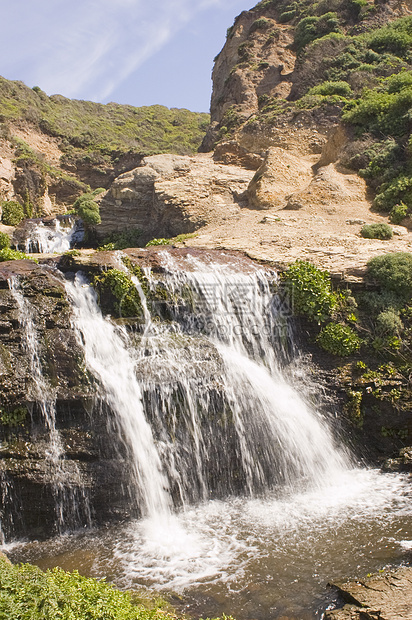 瀑布降于每叶的泉水中溪流悬崖激流海滩图片