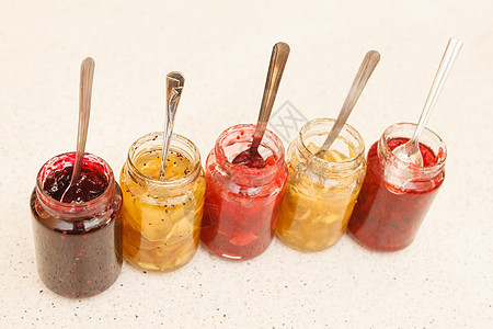装满水果果酱的不同罐子玻璃覆盆子甜点黑色明胶营养果味橙子食物勺子图片