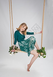在秋千上穿绿裙子的美女头发微笑座位金发赤脚若虫青春期绳索卷曲花朵图片