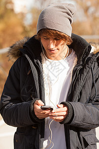 英俊的年轻人在户外咨询电话微笑公园夹克男人耳机图片
