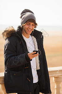 英俊的年轻人在户外咨询电话微笑夹克公园耳机男人图片