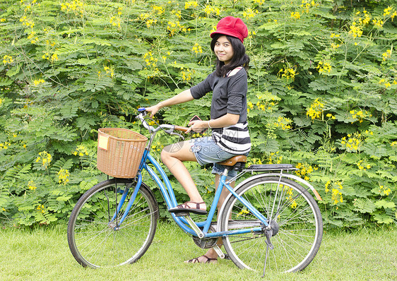 在公园里笑着骑自行车的年轻美女闲暇场地女士快乐骑术娱乐女孩女性活动微笑图片