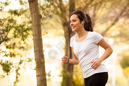 年轻美女慢跑绿色健身房公园拉丁耳机音乐头发肌肉跑步重量图片