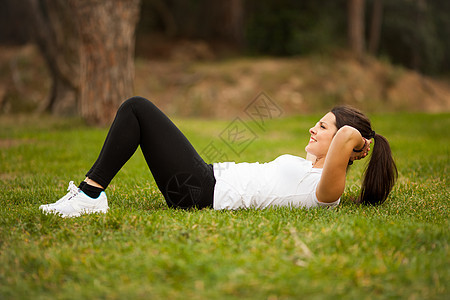 年轻美丽的拉丁女人做腹肌肌肉跑步健身房女士平衡拉丁绿色耳机重量女孩图片