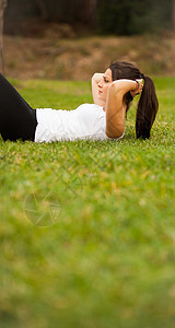 年轻美丽的拉丁女人做腹肌平衡女士跑步耳机绿色女孩音乐头发公园重量图片