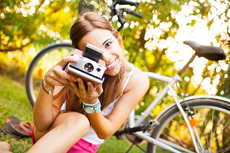 美丽的年轻女子玩着古老的相机自由黄色眼镜女性照片绿色女孩场地手表旅行图片