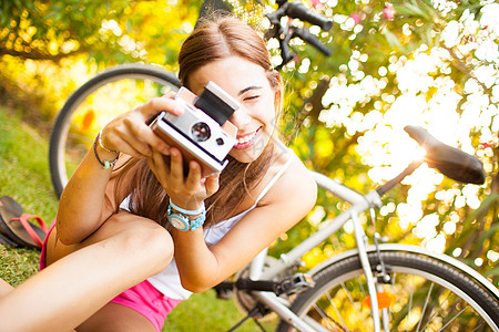 美丽的年轻女子玩着古老的相机黄色自由旅行手表场地绿色女性照片女孩眼镜图片