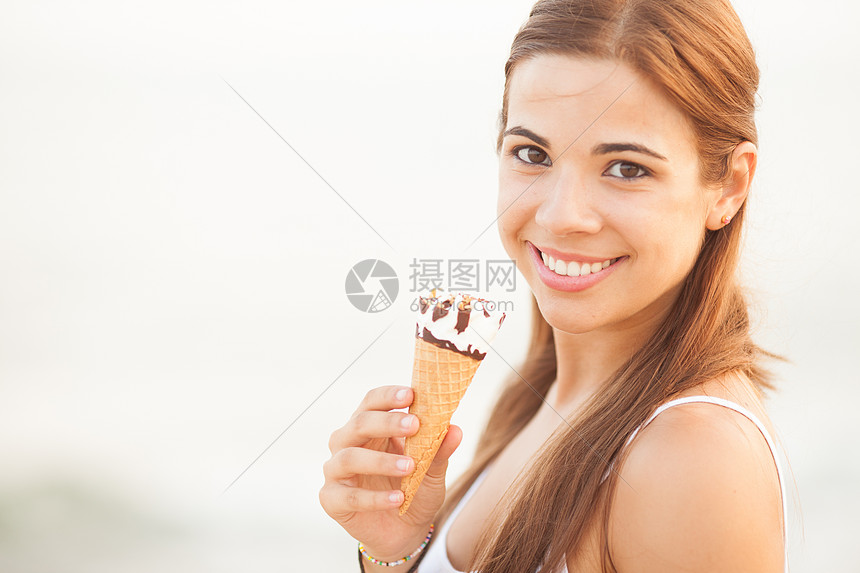 一位年轻美女吃冰淇淋锥的肖像享受锥体头发香草女性奶油美丽幸福微笑白色图片