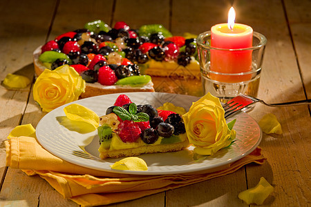 用蜡烛照亮的水果和花瓣餐巾纸浆果奇异果奶油糕点食物桌木甜点玫瑰蛋糕图片