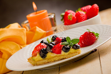 用蜡烛和草莓饼糕点奇异果浆果水果薄荷桌木餐巾纸奶油食物甜点图片