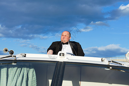穿燕尾服的超重人 在游艇上掌舵蓝色男人甲板黑色天空胖子套装奢华成人图片