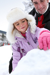 父亲和女儿在雪中玩耍季节父母孩子公园亲戚们拥抱投标乐趣女孩享受图片