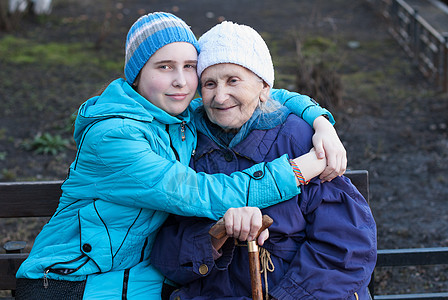 孙女抱着她的外祖母女性友谊蓝色父母老人温暖拥抱肩膀快乐家庭图片