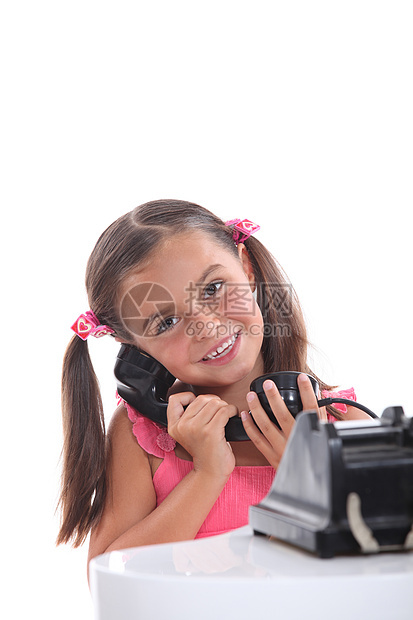 使用旧式黑电话的年轻女孩;图片