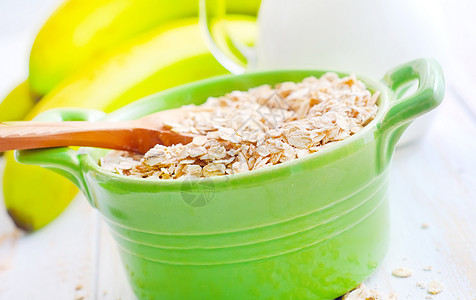 绿碗中含香蕉和牛奶的煤炭片片饮食麦片代谢食物葡萄干薄片玉米木头勺子谷物图片