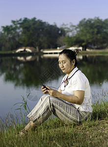 在草地上欢乐的女人 听音乐快乐耳机乐趣女孩女士微笑成人女性说谎幸福图片