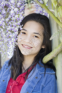 美丽的年轻少女站在葡萄藤下站立着女孩青春期喜悦女性紫色花朵藤蔓混血微笑混血儿图片