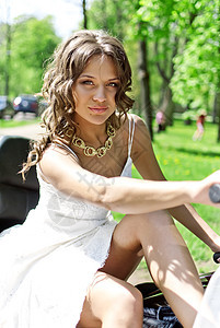 坐在摩托车上的美丽年轻新娘女士白色公园自行车妻子裙子方向盘庆典女孩图片