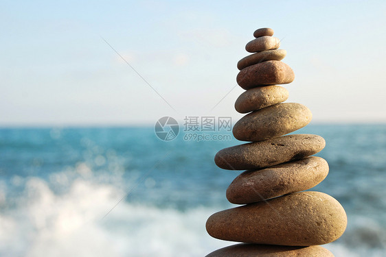 在石头沙滩上的石塔沉思精神蓝色岩石进步团体阳光组织天空平衡图片