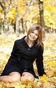 在秋天公园微笑的快乐女孩后代橙子帽子毛衣公园叶子女士少年头发女性图片