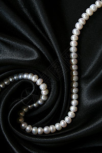 黑色丝绸上的白珍珠作为背景魅力珠子象牙光泽度项链女性宝藏珠宝细绳反射图片