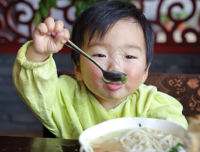 可爱的宝宝在吃东西肩膀面条童年孩子后代托盘食物男生摄影图片