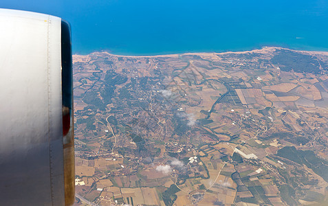 查看飞机的左舷洞太阳蓝色旅行海洋风景城市高度地球航班场景图片