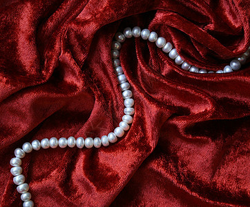 白珍珠项链在天鹅绒上宝藏象牙红色珠子丝绸白色奢华细绳珠宝礼物图片