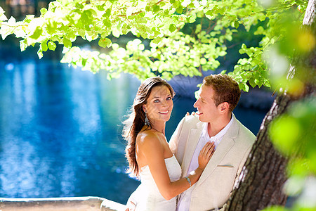 在森林树蓝湖中 情侣的爱拥抱蜜月已婚夫妻妻子庆典丈夫恋人阳光成人公园图片