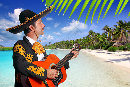 沙滩上弹吉他的墨西哥马利亚奇主义歌手戏服刺绣棕榈男人蓝色边帽热带乐器背景图片