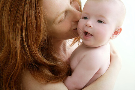 微笑着亲吻小婴儿的母亲宏观女儿家庭孩子儿子金发女孩女士眼睛新生图片