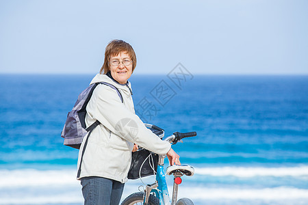 一位在海滩骑自行车的好高贵女士乐趣旅行闲暇假期太阳活动海洋微笑成人运动图片