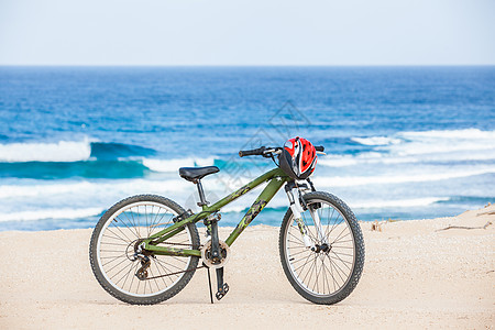 骑着头盔的自行车 站在海滩上海洋娱乐旅行阴影骑术旅游生态冒险运输蓝色图片