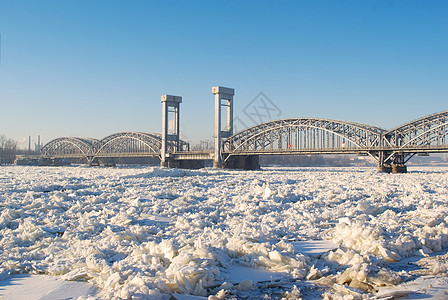 在阳光明媚的天气下 在冰冻河流上架桥蓝色漂移运输铁路季节雪景照片天空历史性建筑学背景