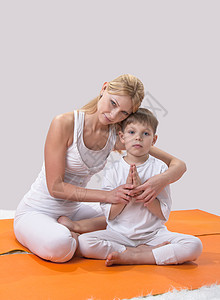 一个美丽的年轻母亲 和儿子一起做瑜伽水平婴儿父母女士姿势头发金发女郎女性运动妈妈图片